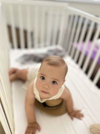 High angle view of cute baby girl sitting on bed at home