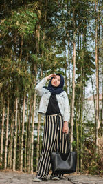 Full length of young woman standing in forest