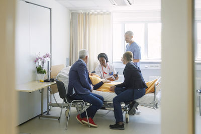 Medical professionals discussing with patient and her friends in ward at hospital