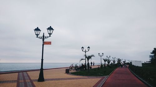 Lamp posts by sea against sky at park