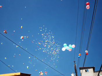 Low angle view of balloons flying against blue sky