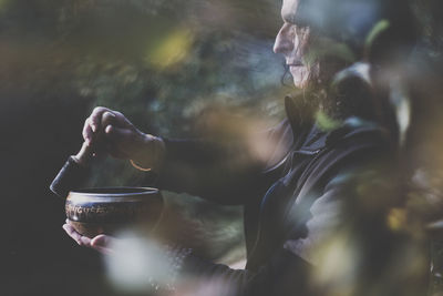 Man playing rin gong while standing in forest