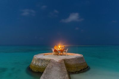 Mature couple doing candlelight dinner on pier in sea