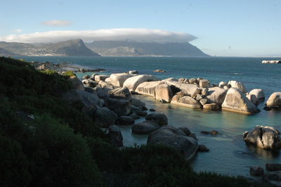 Scenic view of sea by mountains against sky