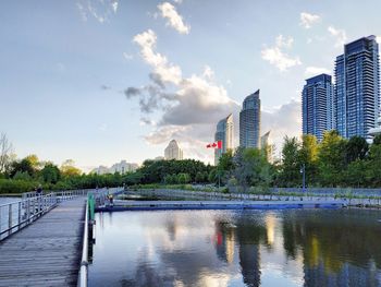 Modern buildings by river against sky