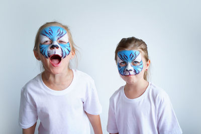 Two sister girls with aqua makeup in the form of a blue water zodiac tiger