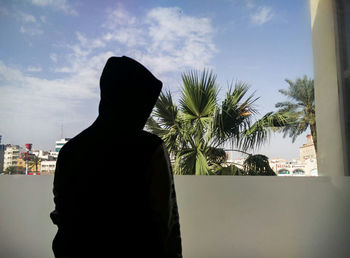 Rear view of man on palm tree against sky