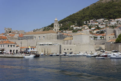 Sailboats in sea against buildings in city