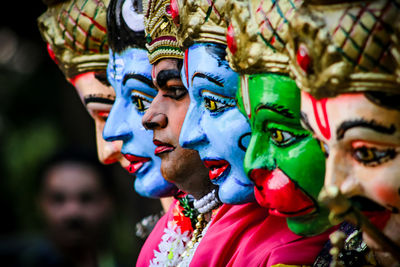 Close-up of man wearing various colorful masks looking away outdoors