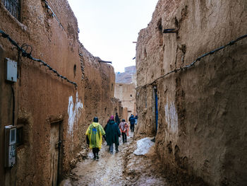 REAR VIEW OF PEOPLE WALKING ON ALLEY