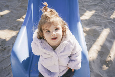 Portrait of cute baby girl sitting on slide