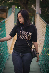 Portrait of young woman standing against railing