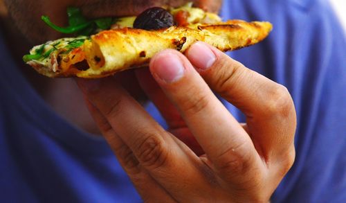 Midsection of man eating pizza