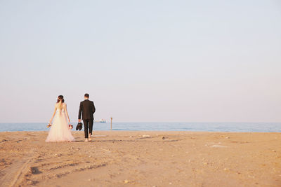 Rear view of bride and groom on beach