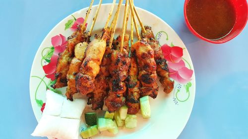 High angle view of fresh chicken satay served on blue table