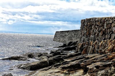 Sea by cliff against sky