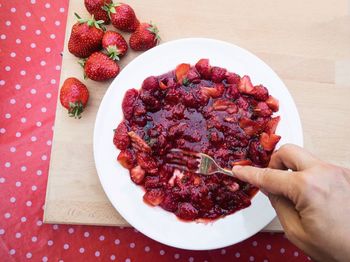 Midsection of man holding strawberries in plate