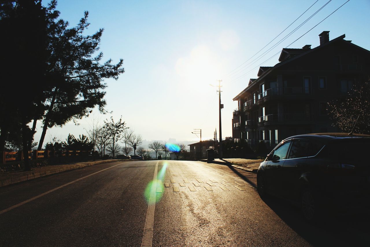 transportation, car, land vehicle, road, street, mode of transport, the way forward, building exterior, sky, built structure, architecture, diminishing perspective, sunlight, road marking, tree, city, city street, street light, vanishing point, on the move