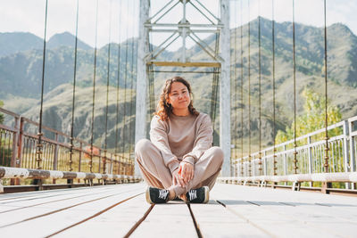 Portrait of young woman sitting on footbridge