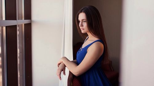 Side view of young woman standing against wall
