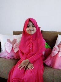 Cute girl sitting on pink blanket at home