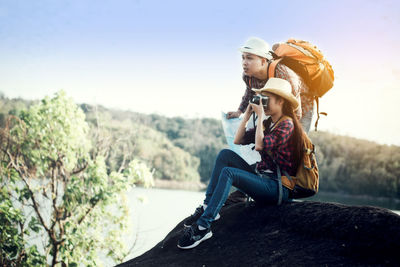 Young couple sitting on mountain against sky