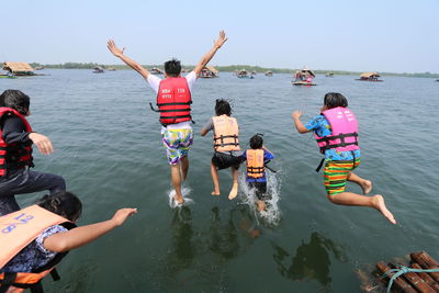 Family diving into lake against sky