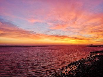 Scenic view of sea against dramatic sky during sunset