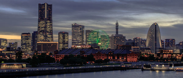 Illuminated buildings in city against sky at dusk