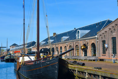 Sailboats moored at harbor against sky in city