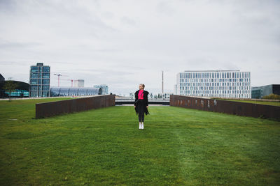 Woman standing on grass against sky