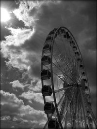 Low angle view of ferris wheel against cloudy sky