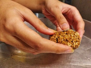 Hands holding rolled oat cookie dough to put on baking tray