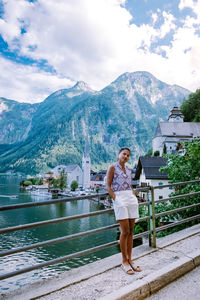 Full length of young woman standing on railing against mountain