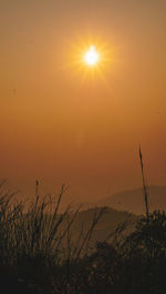 Silhouette landscape against orange sky