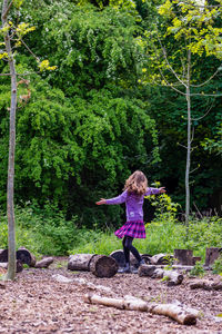 Full length of girl standing on tree trunk