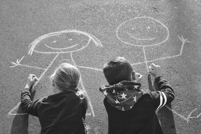 Rear view of friends drawing on footpath