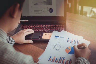 Midsection of businessman working over graph at desk in office