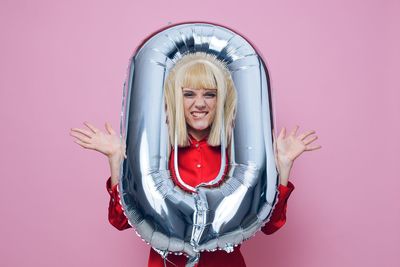 Portrait of woman with arms raised against pink background