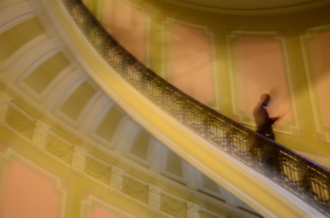 HIGH ANGLE VIEW OF MAN WALKING ON STAIRCASE