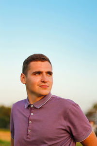 Young man. portrait of smiling young brunette man in purple polo shirt standing outdoor on nature 