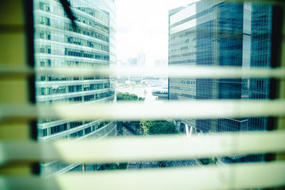 Modern buildings against sky seen through glass window