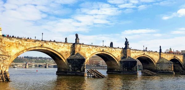 Arch bridge over river against sky in city