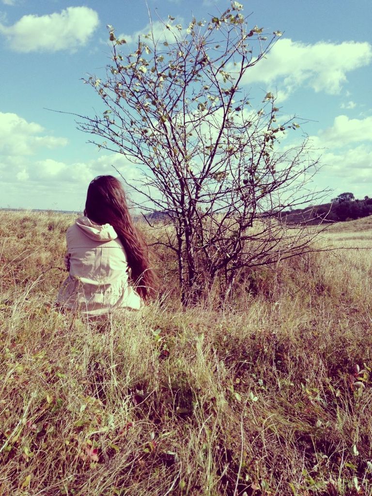 REAR VIEW OF YOUNG WOMAN STANDING ON FIELD