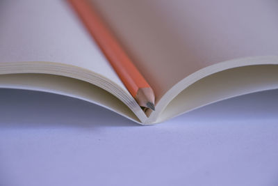 Close-up of pencil in open book over white background