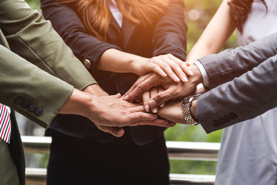 Cropped image of business colleagues stacking hands outdoors