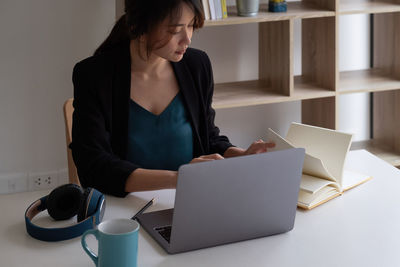 Woman using mobile phone while sitting on table