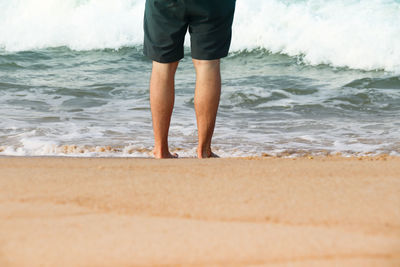 Low section of man standing on beach