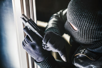 High angle view of burglar with gun standing by window