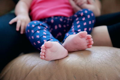 Cropped image of mother and daughter sitting on sofa